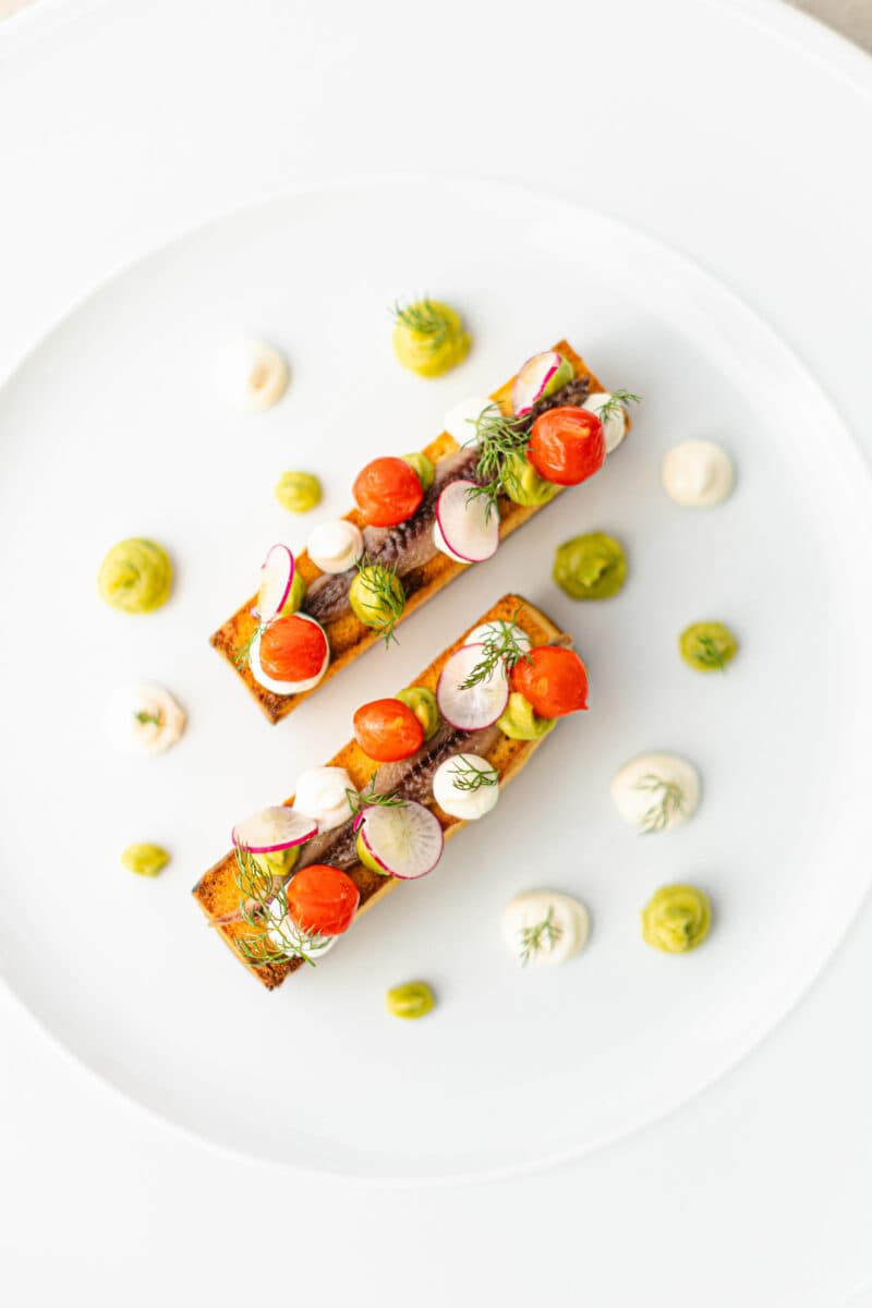 Acciuga del Cantabrico su Pan Brioche Tostato e Imburrato con Cremoso di Avocado, Cremoso al Camembert e fiammelle di Peperone in agrodolce Antipasto